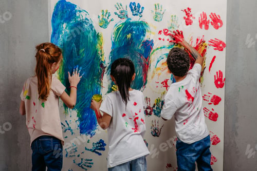 Preview: Rear view of happy kids with finger colours and painted t-shirts, studio shoot.