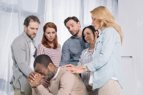 Preview: multiethnic group of people supporting upset african american man during therapy