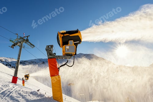 Preview: Operating artificial snow cannon near piste making snowy powder.Ski lift ropeway on hilghland alpine