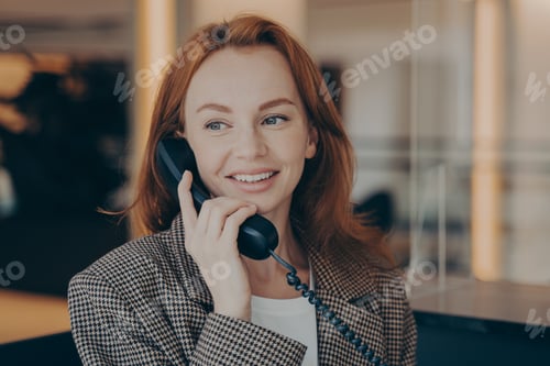 Preview: Portrait of satisfied female office worker using black landline phone, calling business partner