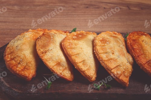 Preview: fried chebureks, deep-fried, mini, on a chopping board, wooden table, close-up, no people,