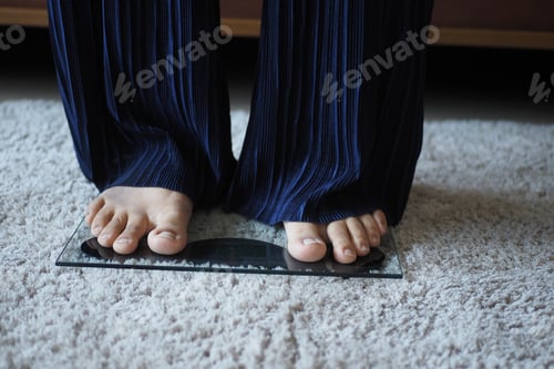 Preview: woman's feet on weight scale close up.