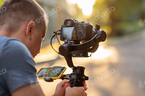 Preview: Young Caucasian man filmmaker makes a video footage via photo camera and using modern technology