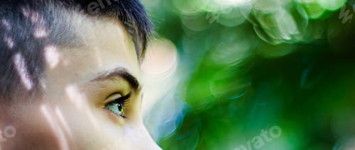 Preview: Eyes of a boy in profile with a blurred green background