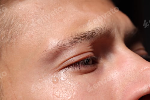 Preview: Sad man crying on black background, closeup