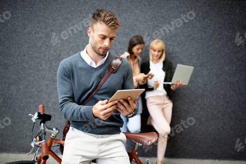 Preview: Group of happy young business people holding different digital devices outdoor