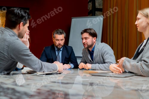 Preview: office workers are sitting in a conference room with red walls led by a director actively discussing