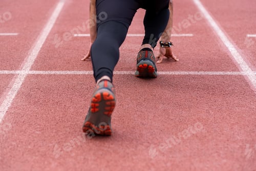 Preview: legs of professional sportsman in starting position, run along rubberized track at outdoor stadium