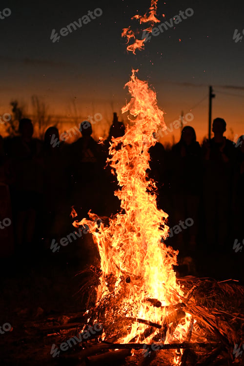 Preview: strong vertical flame shoots upward, illuminating the silhouettes of onlookers in darkness.