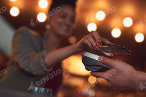 Preview: Closeup shot of a woman paying using NFC technology in a cafe