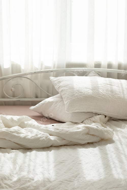 Preview: White linen textile bedclothes. Pile of pillows. Cozy bedroom interior and beautiful morning light