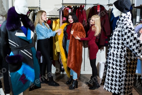 Preview: Three women trying on a fur coat in the store