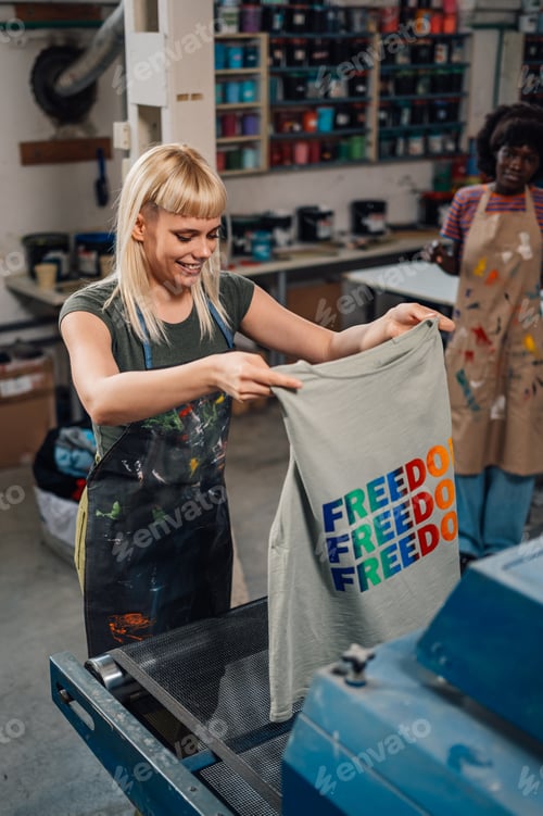 Preview: Smiling print shop female worker putting product into a drying machine