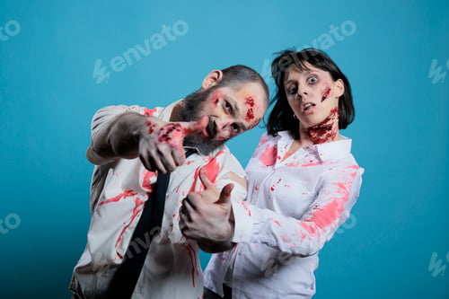Preview: Couple doing photoshoot dressed as zombies for Halloween, studio background