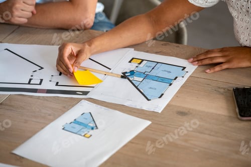 Preview: Hands collaborating on architectural floor plans on a table.