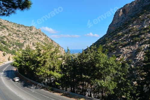 Preview: Mountain road, hills with green trees, sea on the horizon, summer blue sky