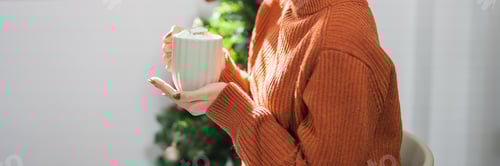 Preview: Woman Holding Cocoa by Christmas Tree Indoors