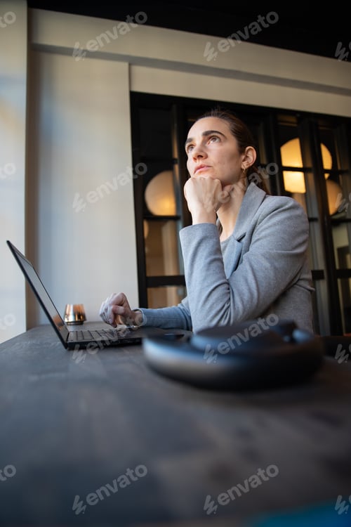 Preview: business woman with thoughtful expression while working in the office puts her hand under her chin