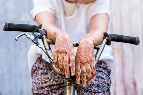 Preview: Woman with henna tattoo on hands sitting on bicycle