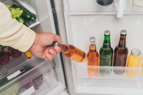 Preview: cropped view of man taking bottle of beer out of fridge