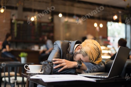 Preview: Tired businessman cup take a nap at cafe while working with his laptop.