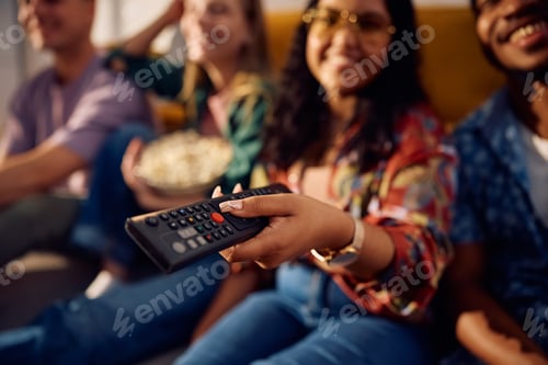Preview: Close up of friends watching movie on TV at home.