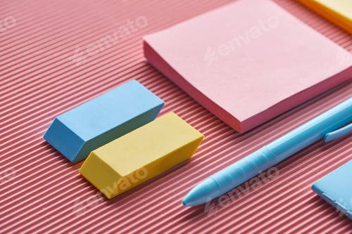 Preview: close up of sticky notes, erasers and pen on pink