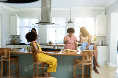 Preview: Young biracial female friends preparing pizza on kitchen island and spending leisure time at home