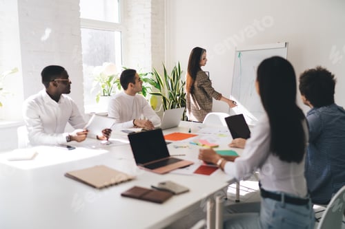 Preview: Female speaker drawing diagram on flip chart during meeting with diverse colleagues