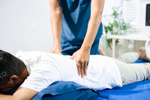 Preview: Male physiotherapist performs spine and arm adjustment therapy for patient on bed.