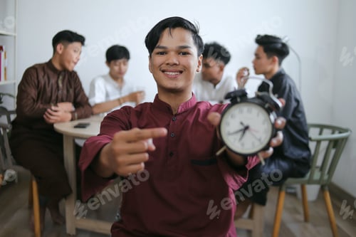 Preview: Asian Muslim Man Holding Alarm Clock Showing Iftar Time While His Friends Enjoying Food