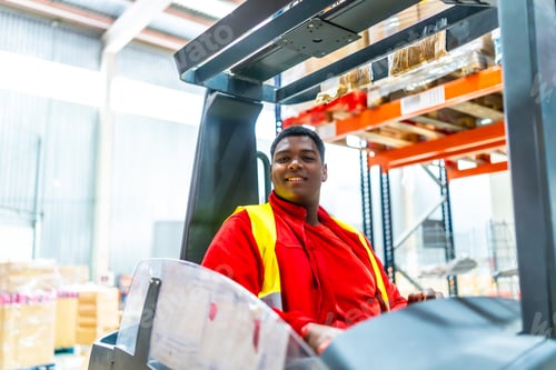 Preview: Happy manual worker driving forklift in a factory