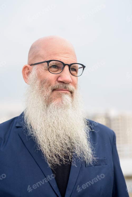 Preview: Face of mature bald bearded businessman with eyeglasses thinking outdoors