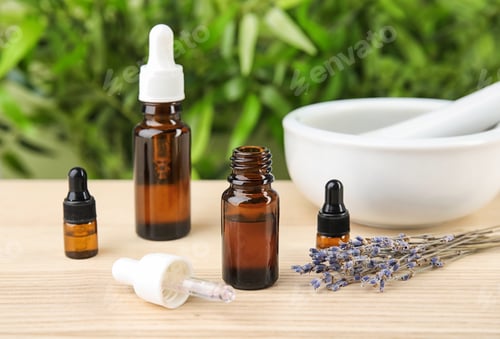 Preview: Bottles with natural herbal oil and lavender flowers on table against blurred background