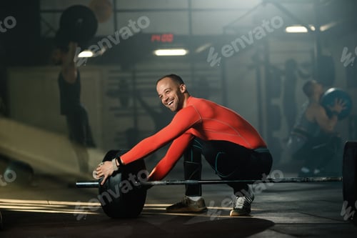 Preview: Happy sportsman preparing barbell for weight training in a gym.