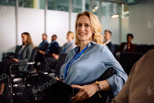 Preview: Happy female entrepreneur attending a business conference and looking at camera.