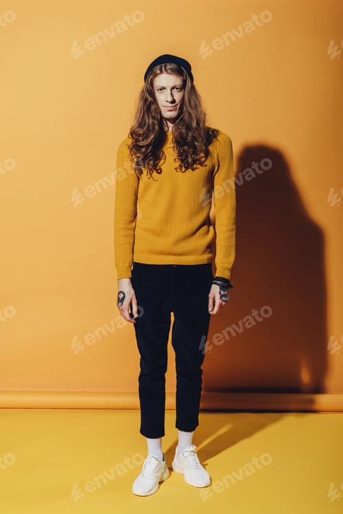 Preview: fashionable man standing and looking at camera, on yellow