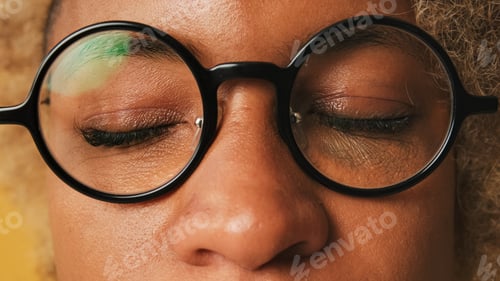 Preview: Close-up of girl in glasses with closed eyes isolated on orange background