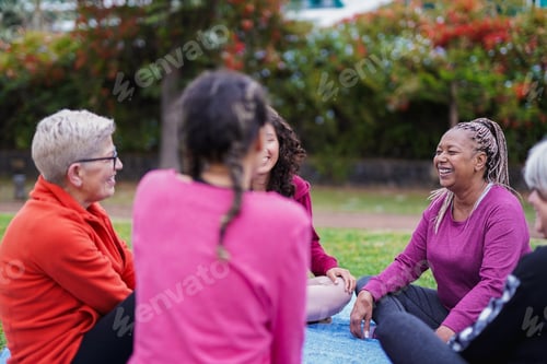 Preview: Group of happy multi generational women having fun sitting in a circle at city park