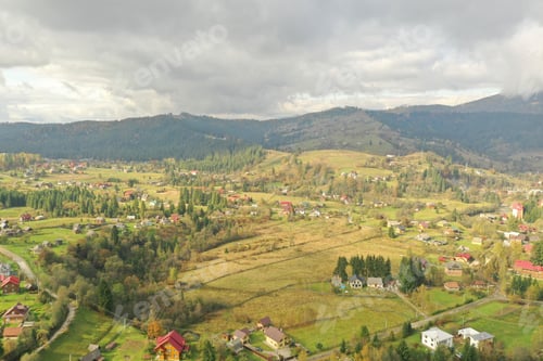 Preview: Aerial view of beautiful forest and mountain village on autumn day
