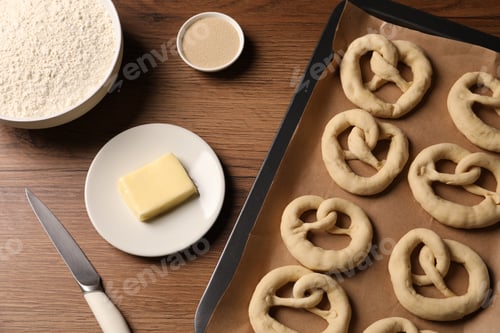 Preview: Uncooked pretzels and ingredients on wooden table, flat lay