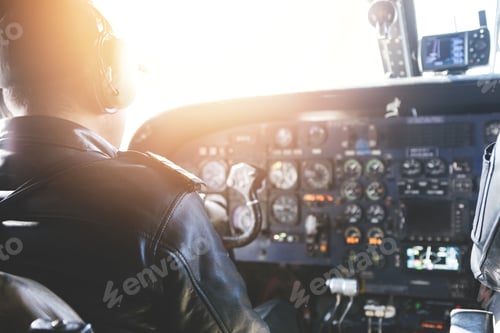 Preview: Adult airplane pilot wearing headset and outfit performing his job, sitting inside aircraft cockpit
