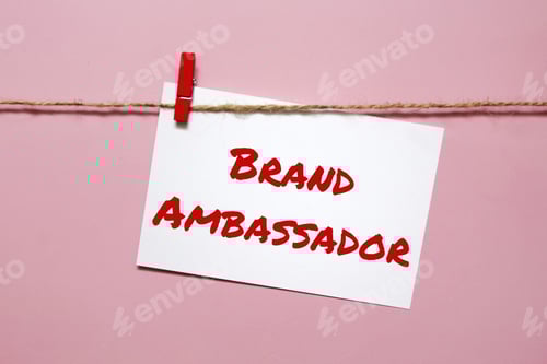 Preview: Sticker with the inscription brand ambassador hanging on a rope on a pink background