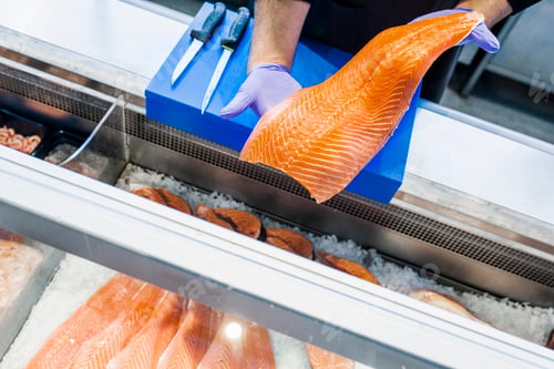 Preview: Cropped image of fish vendor holding salmon at supermarket