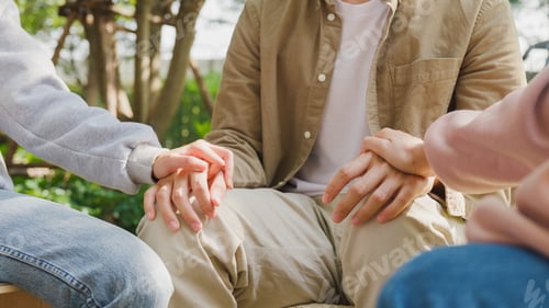 Preview: Close-up of diverse multiracial men and women group sit in circle hold hands together hope.