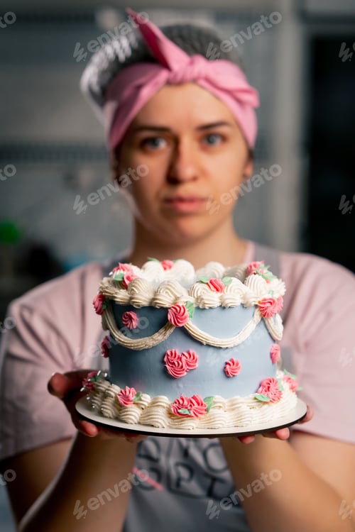 Preview: close-up in a professional kitchen a female baker stands with a finished cake in her hands