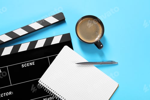 Preview: Movie clapper, coffee, notebook and pen on light blue background, flat lay