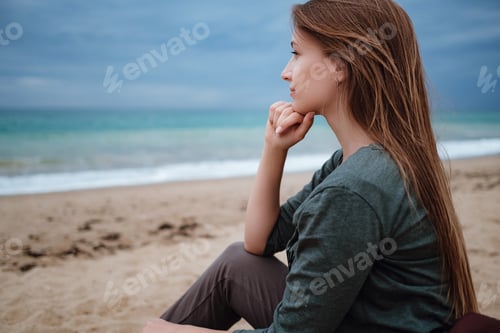 Preview: woman enjoying sea air on autumn beach before thunderstorm.