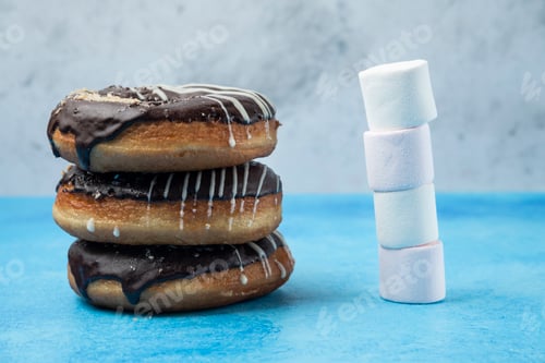 Preview: Stack of chocolate donuts and marshmallows on blue table