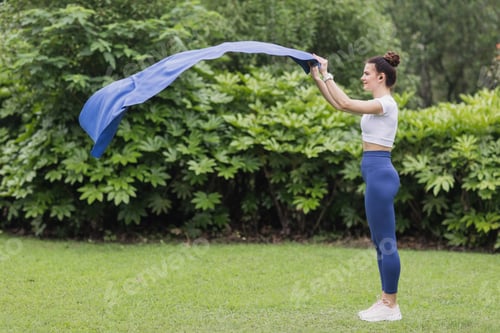Preview: happy young sporty yoga coach teacher preparing fitness mat for exercising outdoor in summer park